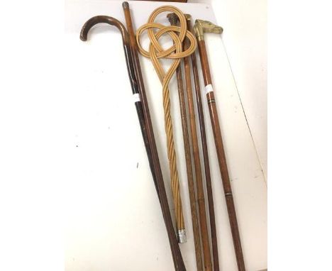 A collection of walking sticks, including a segmental cane with brass horse head finial, a malacca cane with white metal top,