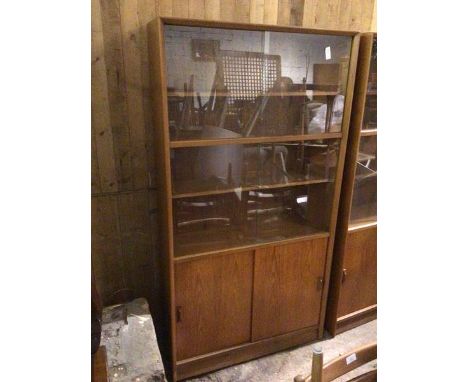 A mid century teak tall wall unit, fitted sliding glass panels enclosing an interior fitted four shelves, above sliding panel