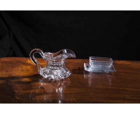 A 19TH CENTURY CUT GLASS JUG, the wide spout and c-scroll handle set into a shallow heavy star-cut base. 10cm tall x 15cm wid