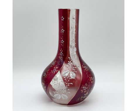 A stunning art glass vase featuring a rich ruby-red overlay with intricate floral and botanical engravings. The design incorp