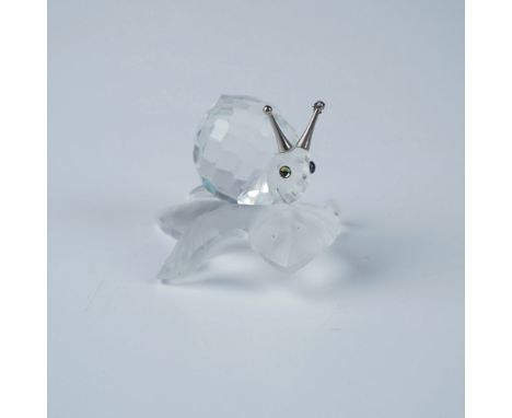 Swarovski crystal figurine featuring a faceted snail resting on a frosted vine leaf. The snail's shell is intricately cut to 