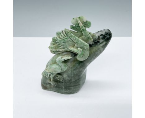 A meticulously carved jade sculpture featuring an intricate design of birds perched amidst foliage. The vibrant green hues an
