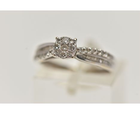 A WHITE METAL DIAMOND CLUSTER RING, designed as a circular cluster of round brilliant cut diamonds, flanked with single cut a