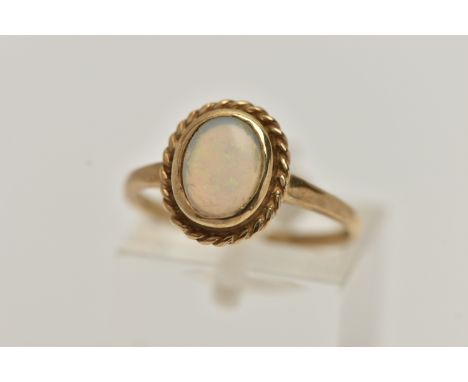 A 9CT GOLD OPAL CABOCHON RING, oval cut opal cabochon, collet set with a fine rope twist surround, polished band hallmarked 9