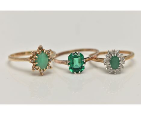 THREE GEM SET RINGS, the first an oval cut emerald set with a surround of round brilliant cut diamonds, prong set in white go