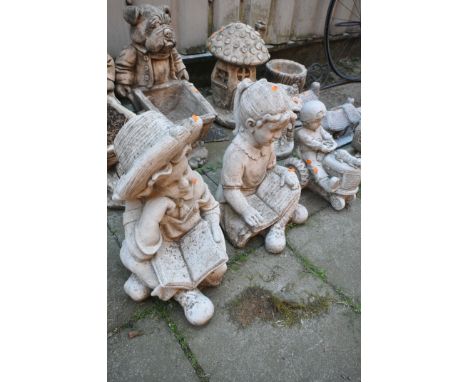TWO WEATHERED COMPOSITE FIGURAL ITEMS, of a boy and girl sitting and reading, along boy riding a tractor (condition report: -