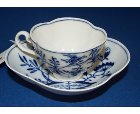 A Meissen porcelain teacup and saucer, decorated flowers and foliage in underglaze blue (handle chipped and cracked)
