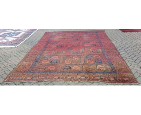 An Afghan carpet, decorated geometric motifs on a red ground, 391 x 262 cm