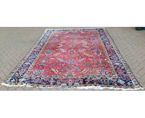 A Persian Heriz carpet, with stylised floral motifs on a red ground, 328 x 233 cm