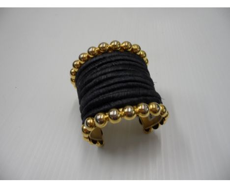 Nina Ricci cuff bangle, woven black banding with large gold coloured balls to borders (one ball has detached from the other b