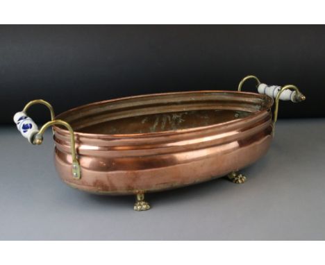 Copper Oval Planter with ceramic handles and raised on four brass lion paw feet, 43cms long 