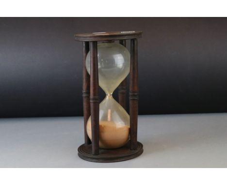 Glass Sand Timer held within a Mahogany Frame with turned supports, 23cms high 
