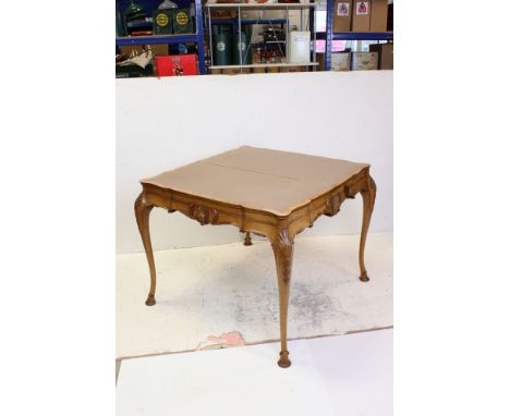 French style Maple and Walnut Fold-over Card Table with pale brown playing surface, shaped top, frieze carved with a face mas