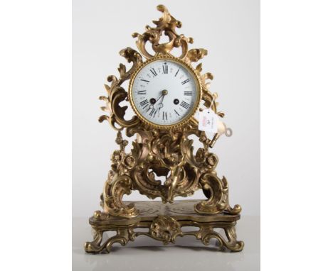 Brass cased French style clock, with ornate Rococo case  with scrolls and floral swags, white enamel dial with a Roman numera