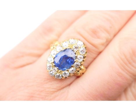 Sapphire and diamond cluster ring, set with a central cornflower blue cushion cut oval sapphire, approx. 10mm x 8mm, surround