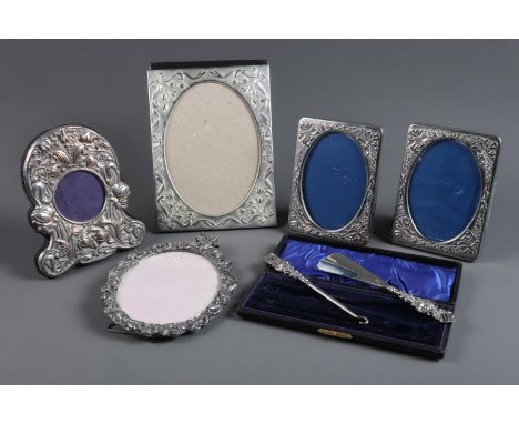 A pair of white metal photo frames with embossed decoration, three other photo frames and a white metal shoe horn and button 