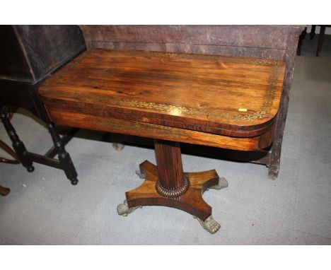 A Regency rosewood and brass inlaid fold-over top card table, on reeded column and quatreform base with bronze lion paw feet,