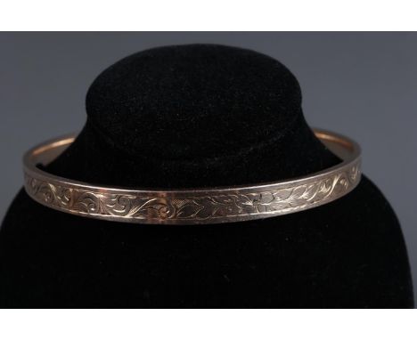 A 9ct gold bangle with metal core and engraved scrolled decoration, 3" dia