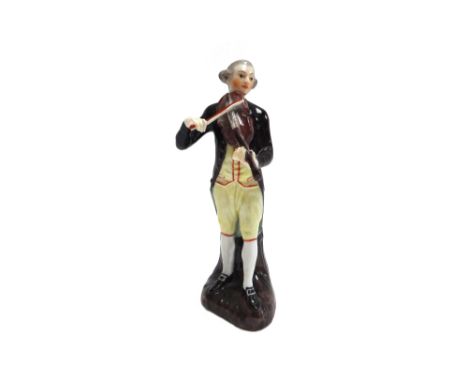 A Continental porcelain figure of a musician, possibly Thuringian, late 18th century, modelled as a man standing before a tre