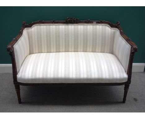 A late 19th century square back sofa, with extensive floral carved mahogany frame and striped cream upholstery, on spiral flu