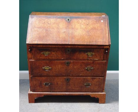 A George I walnut bureau, with fitted interior over three long graduated drawers on bracket feet, with paper label 'CECIL A H