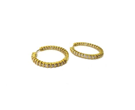 A pair of 18ct gold and diamond set hoop shaped earrings, of hinged form, mounted with rows of circular cut diamonds, detaile