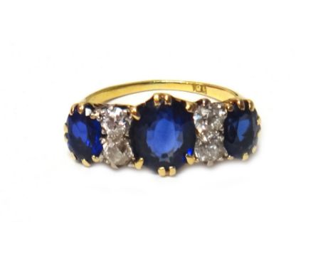 A gold, diamond, sapphire and synthetic sapphire ring, mounted with the oval cut synthetic sapphire at the centre, between tw