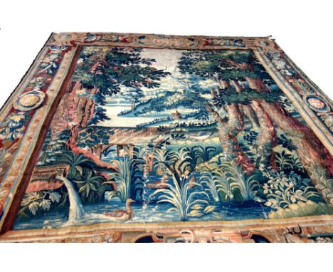 A French verdure tapestry, late 17th century, depicting a pastoral landscape with lake, mountains and wooded scene, ducks and