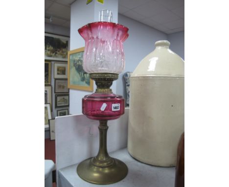A Brass Oil Lamp, circa 1900 with eighteen facets to cranberry glass well, etched and tinted shade.