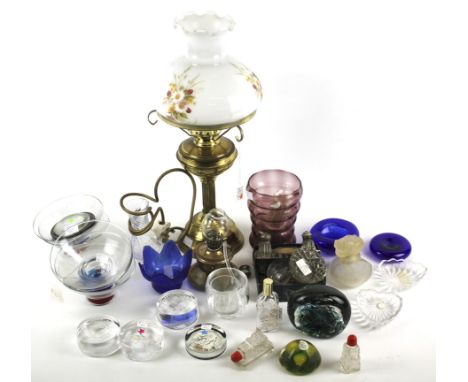 An assortment of glassware and a brass oil lamp. Including vases, paperweights, bowls, etc, the oil lamp with a glass shade d