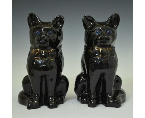 Pair of glazed terracotta cats, each with blue glass eyes and wearing a bow tie collar, 33cm high