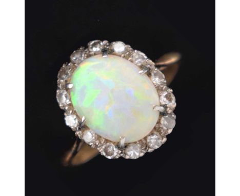 Opal and diamond cluster ring, the shank stamped '18ct PL', the oval cabochon measuring approximately 8mm x 10mm, within a bo
