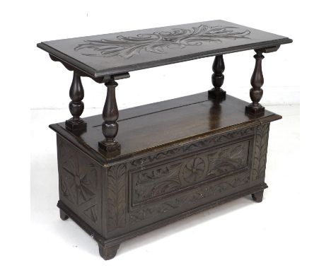 A stained and carved oak monk's bench, mid 20th century, with lifting and sliding top, a/f top and arms loose requiring repai