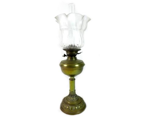 A Victorian brass paraffin lamp, with brass reservoir above column, on a circular base, with clear glass chimney and moulded 