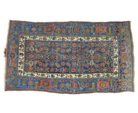 A Persian rug with dark blue ground, floral decoration all over, cream and light blue borders, 119 by 212cm. 