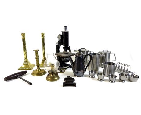 A group of metalware, including a pair of brass candlesticks, a brass ejector candlestick, a microscope, a cast iron doorstop