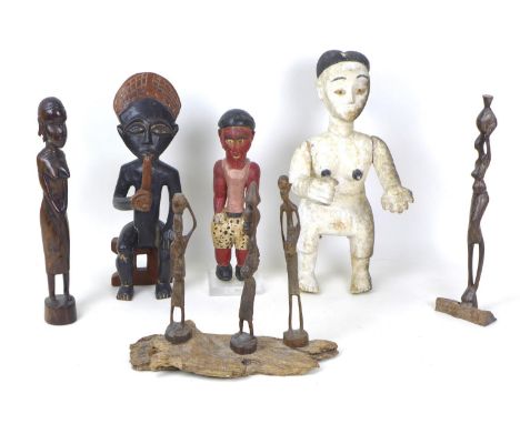 A group of wooden figures mostly African, including a black and white painted figure with her arms outstretched, 37cm high, a