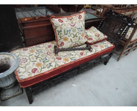 A late Victorian dark oak day bed having twist and armorial decoration to frame with later tapestry squab cushions over canew