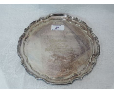 A silver card tray of shaped circular form having a raised pie crust rim, inscription to centre and trefoil shell feet, Sheff