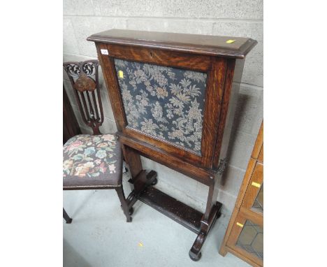 A late Victorian oak escritoire having open top with tapestry panel and brass scorce on slender trestle frame