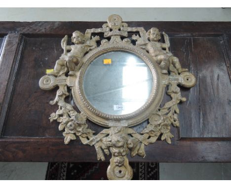 A vintage cast metal wall mirror having Heraldic crest and puttie decoration