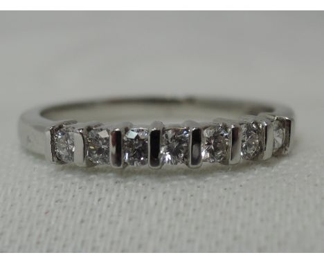 A lady's half eternity ring having seven diamond chips in a tension mount on a platinum loop, size K