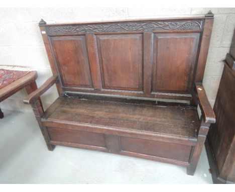 A late Victorian dark oak hall bench having vine carved frieze, panel back over box seat