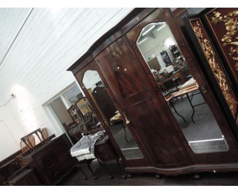 An early 20th century mahogany bedroom suite in the Chippendale revival style comprising bow front mirror door wardrobe, trip