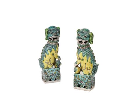 A pair of 19th or early 20th century pair of Chinese Famille Verde Buddhist Lions, standing facing to the left and right, one