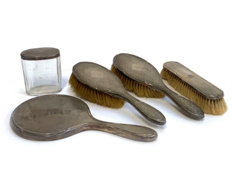 An engine turned silver dressing table set, comprising clothes brush, two hairbrushes, and looking glass, hallmarked Chester 