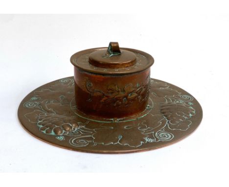 An Arts &amp; Crafts Newlyn school copper inkwell, the rim chased with grape and vine decoration, stamped indistinctly to bas