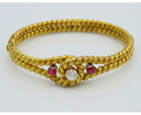 A yellow metal rope style bangle set with red & white imitation diamond & ruby, tests electronically as 18ct gold, internal m