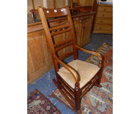 A LATE VICTORIAN ROCKING CHAIR WITH LADDER BACK AND RUSH SEAT.