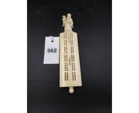 A CHINESE IVORY CRIBBAGE BOARD WITH CARVED FIGURAL HANDLE AND PEG HOLDER IN BASE.